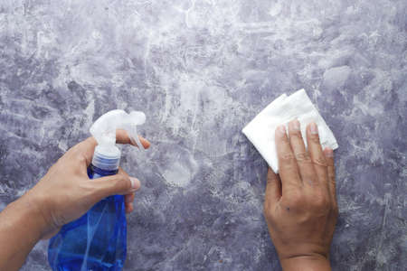 hand holding spray bottle cleaning tableの写真素材