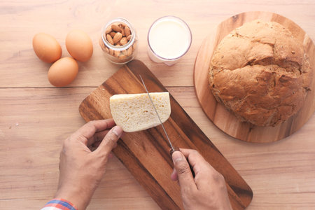 flat composition of of man hand cutting cheese on chopping boardの写真素材