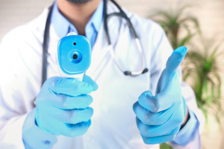 Hand holding infrared thermometer to measuring temperature.