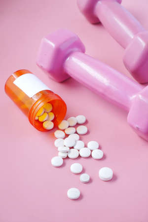 pink color dumbbell and medical pills on pinkの写真素材