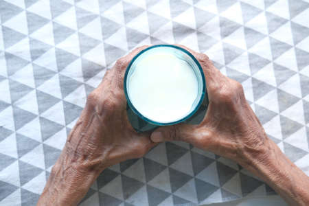 senior women hand holding a glass of milkの写真素材