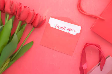 thank you message on paper with tulip flower on red backgroundの写真素材