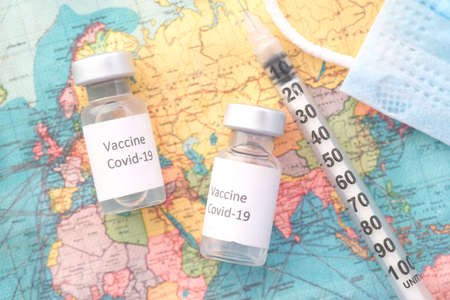 Close up of coronavirus vaccine and syringe on a travel mapの写真素材
