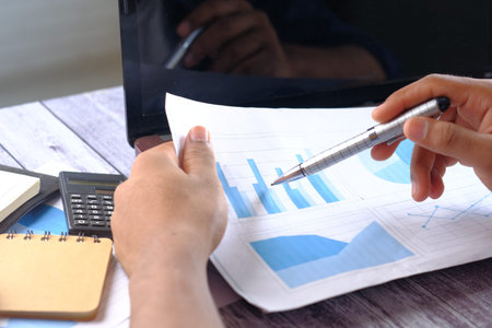man hand with pen analyzing bar chart on paper