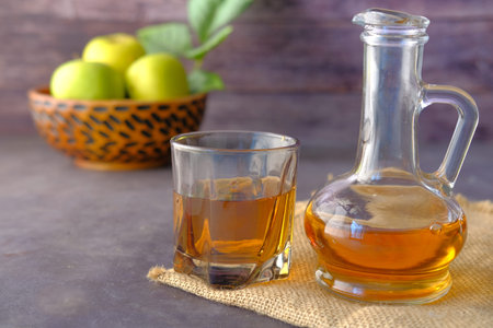 apple vinegar in glass bottle with fresh green apple on table