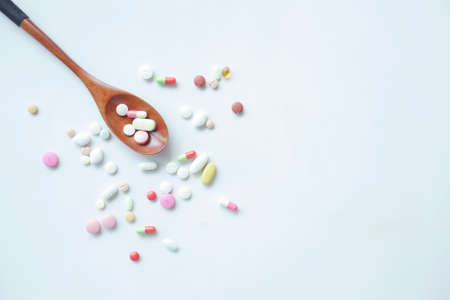 top view of many colorful pills and capsules on spoon on tableの写真素材