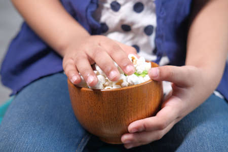 child girl hand holding a bowl of colorful popcornの写真素材