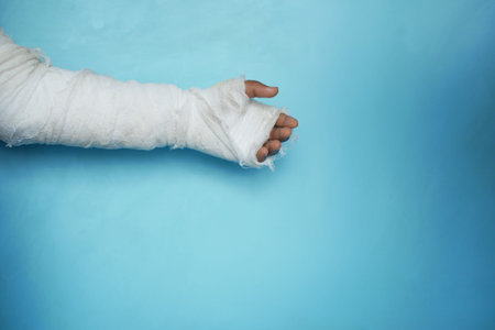 injured painful hand with bandage against blue background