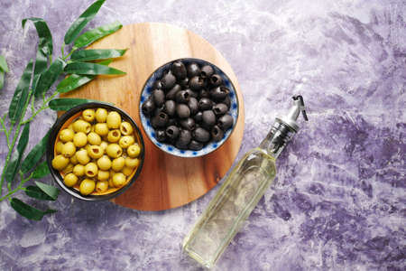 bottle of olive oil, fresh green and black olive in a container on table .の写真素材
