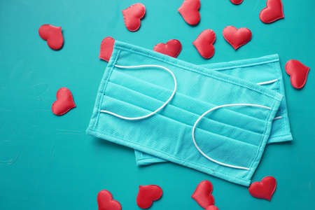 Surgical masks with heart shape and hand sanitizer on color backgroundの写真素材