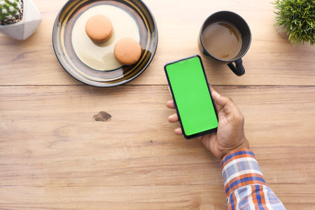 top view of man hand using smart phone on office desk