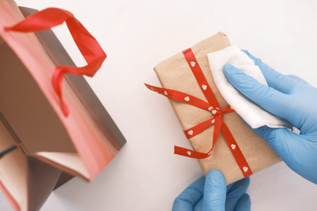 hand in latex gloves wapping a gift box with tissueの写真素材