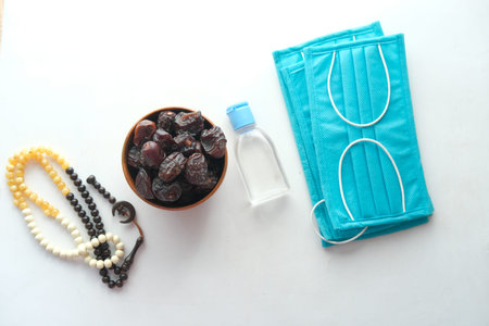 fresh date fruit in a bowl , prayer rosary , hand sanitizer and mask on floor