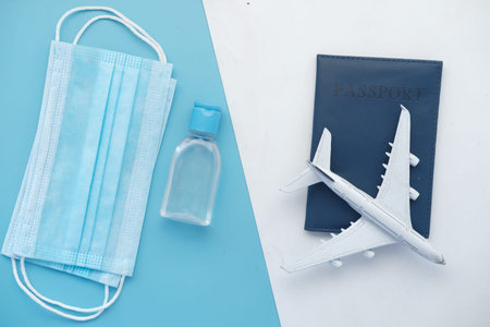 protective mask, airplane and blue color passport on table