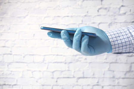 hand in latex gloves holding smart phone with green screenの写真素材