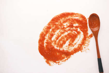 tomato sauce and a wooden spoon on white backgroundの写真素材