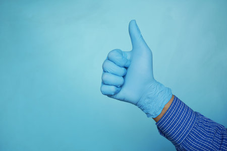 man hand showing a thumb-up on blue backgroundの写真素材