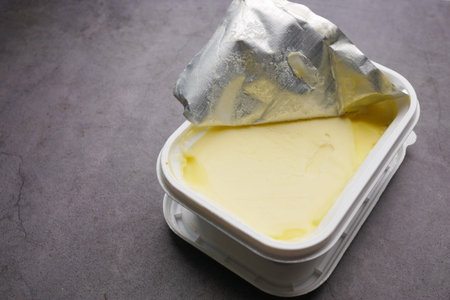 salted butter in a container on black background
