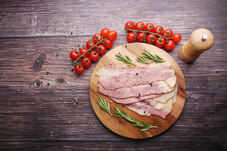Raw fed bacon strips on chopping board .の写真素材
