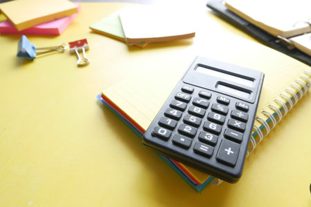 Close up of blue calculator and notepad on color background
