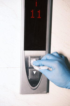 Man hand in protective gloves disinfecting elevator buttons.の写真素材