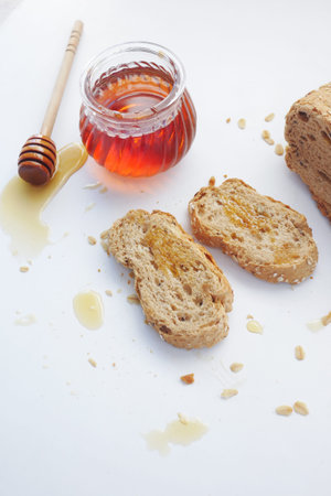 Sliced whole grain bread with oat flakes and honey on whiteの写真素材