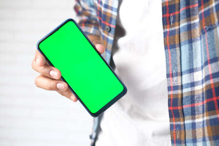 Close up of young man hand using smart phone with green screenの写真素材