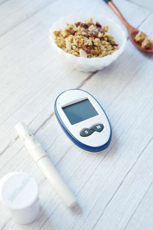 diabetic measurement tools and healthy breakfast cereal in a bowl on tableの写真素材