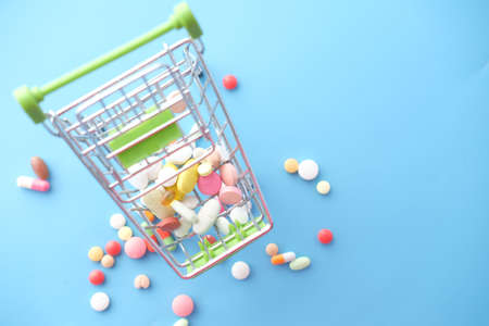 top view of many colorful pills, capsules and shopping card on blue backgroundの写真素材