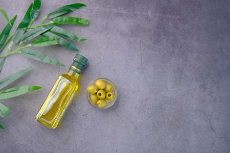 bottle of olive oil and fresh olive in a container on black background .の写真素材