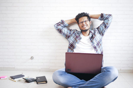 sad man working on laptop at home while sited on floorの写真素材