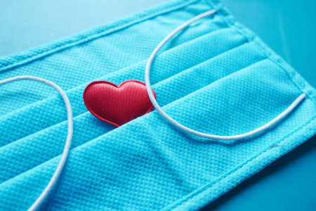 Surgical masks with heart shape and hand sanitizer on color backgroundの写真素材
