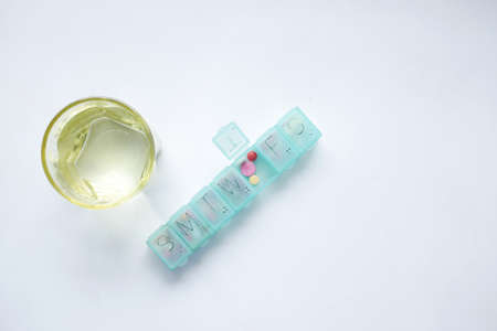 pill box fill with medical capsule and glass on white backgroundの写真素材