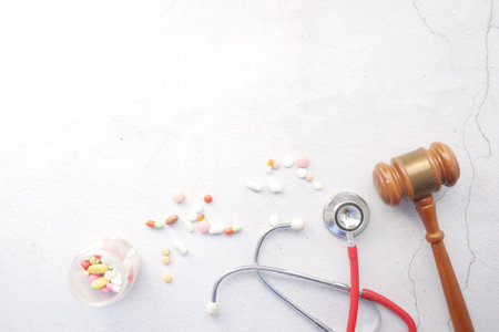 Top view of gavel, stethoscope and pills on white background
