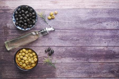 bottle of olive oil, fresh green and black olive in a container on table .の写真素材