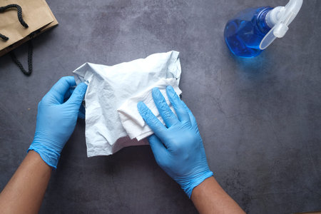hand in blue rubber gloves holding spray bottle cleaning delivery package