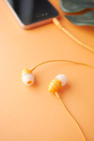 smart phone with empty screen, earphone on orange backgroundの写真素材