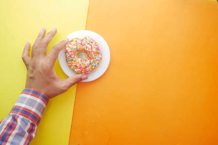 hand pick fresh colorful donuts on color backgroundの写真素材