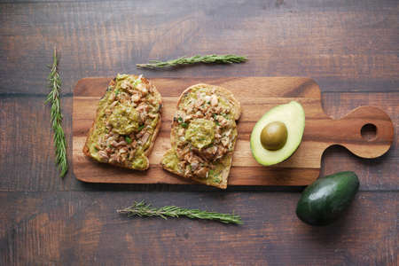 Avocado, brown bread, tuna fish on chopping board on tableの写真素材