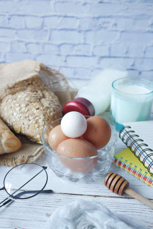 eggs in a bowl, whole meal bread and milk on tableの写真素材