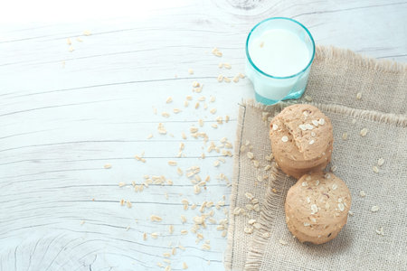 stack of whole meal cookies and glass of milk on wooden background