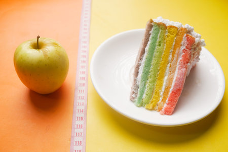 measuring tape, green apple and a bakery cake on color background