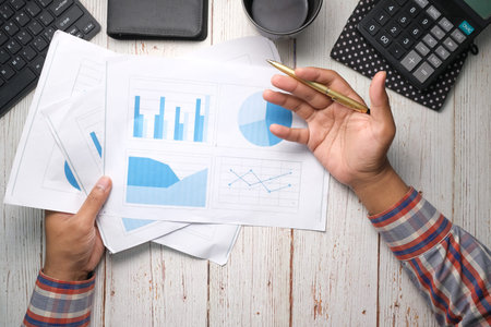 man hand with pen analyzing bar chart on paper