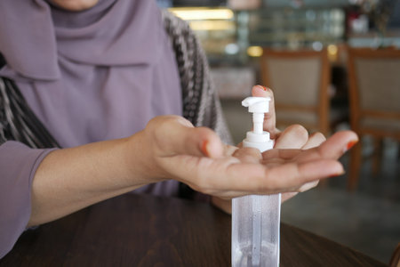 young women using hand sanitizer at cafeの写真素材