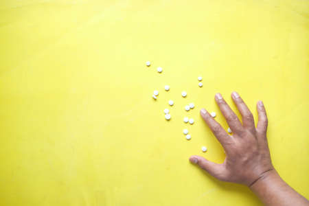 white color medical pills spilling on yellow backgroundの写真素材