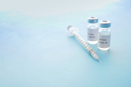 coronavirus vaccine and syringe on blue background