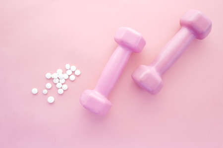 pink color dumbbell and medical pills on pinkの写真素材