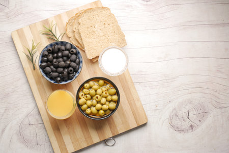 brown bread, juice, fresh green black olive in a container on table .の写真素材