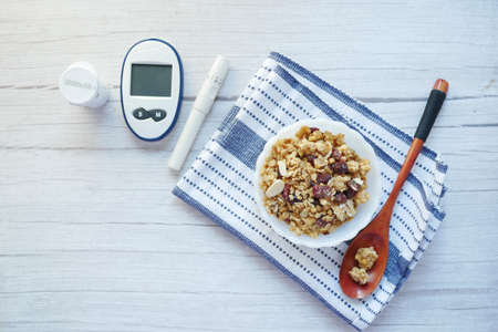 diabetic measurement tools and breakfast cereal in a bowl on tableの写真素材