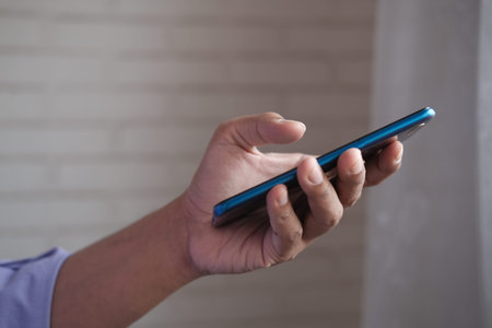Close up of young man hand using smart phone indoorの写真素材